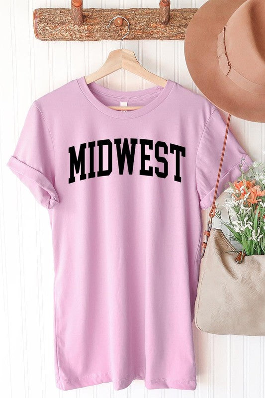 A light pink Unisex Crew Neck Midwest Graphic Tee, featuring rolled sleeves and the word "MIDWEST" printed in bold black letters, hangs on a wooden hanger. This tee makes a perfect addition to your Family Group Uniforms.