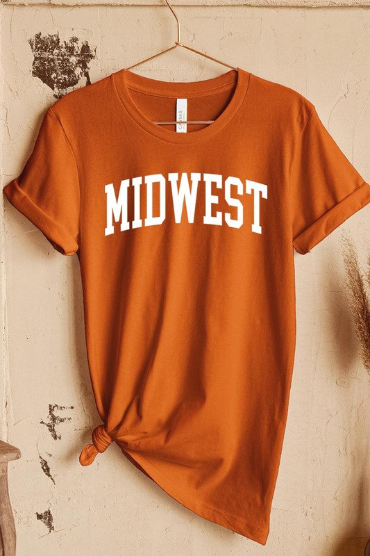 A light pink Unisex Crew Neck Midwest Graphic Tee, featuring rolled sleeves and the word "MIDWEST" printed in bold black letters, hangs on a wooden hanger. This tee makes a perfect addition to your Family Group Uniforms.