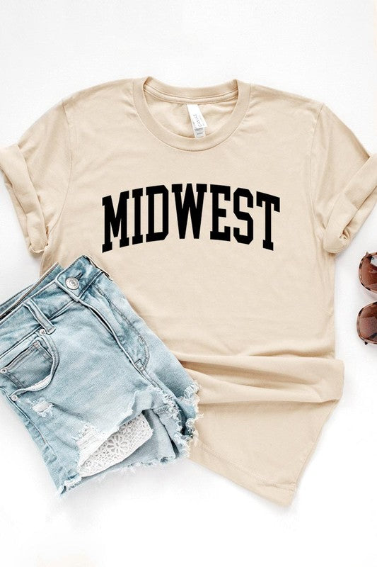 A light pink Unisex Crew Neck Midwest Graphic Tee, featuring rolled sleeves and the word "MIDWEST" printed in bold black letters, hangs on a wooden hanger. This tee makes a perfect addition to your Family Group Uniforms.