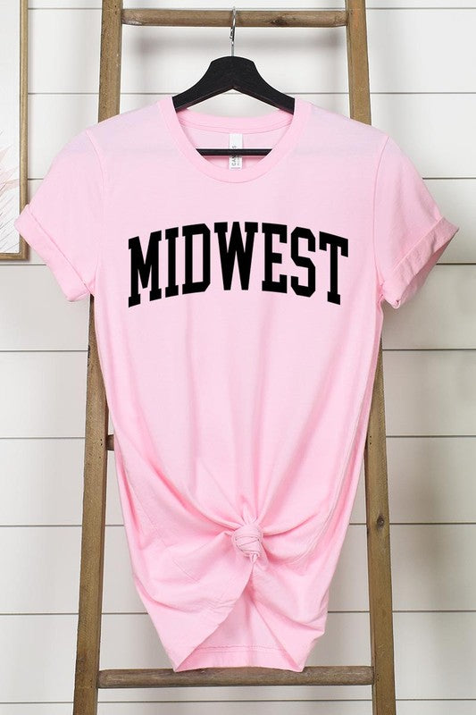 A light pink Unisex Crew Neck Midwest Graphic Tee, featuring rolled sleeves and the word "MIDWEST" printed in bold black letters, hangs on a wooden hanger. This tee makes a perfect addition to your Family Group Uniforms.