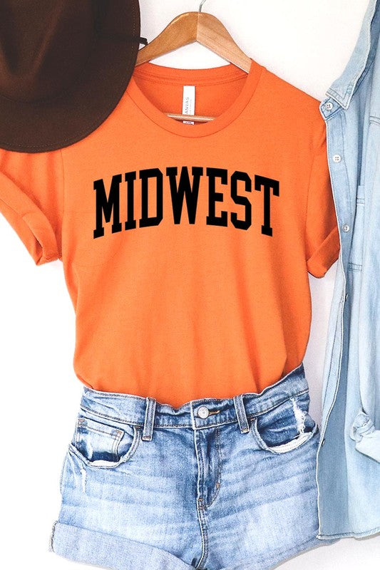 A light pink Unisex Crew Neck Midwest Graphic Tee, featuring rolled sleeves and the word "MIDWEST" printed in bold black letters, hangs on a wooden hanger. This tee makes a perfect addition to your Family Group Uniforms.