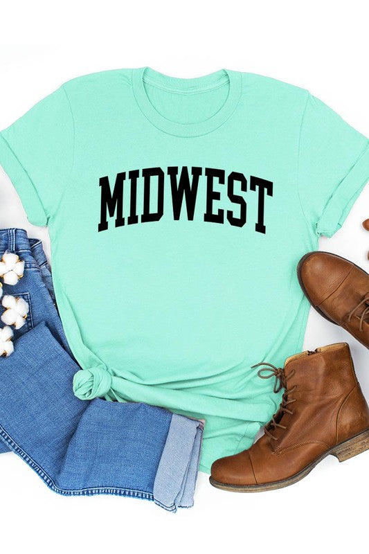 A light pink Unisex Crew Neck Midwest Graphic Tee, featuring rolled sleeves and the word "MIDWEST" printed in bold black letters, hangs on a wooden hanger. This tee makes a perfect addition to your Family Group Uniforms.