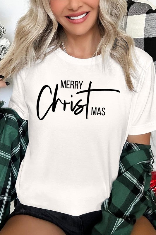 A woman with long blonde hair is smiling while wearing a Merry Christmas Graphic Tee featuring "Merry Christmas" in white script. This unisex crew neck tee boasts a high-quality direct-to-film printed graphic design that ensures vibrant and lasting colors.