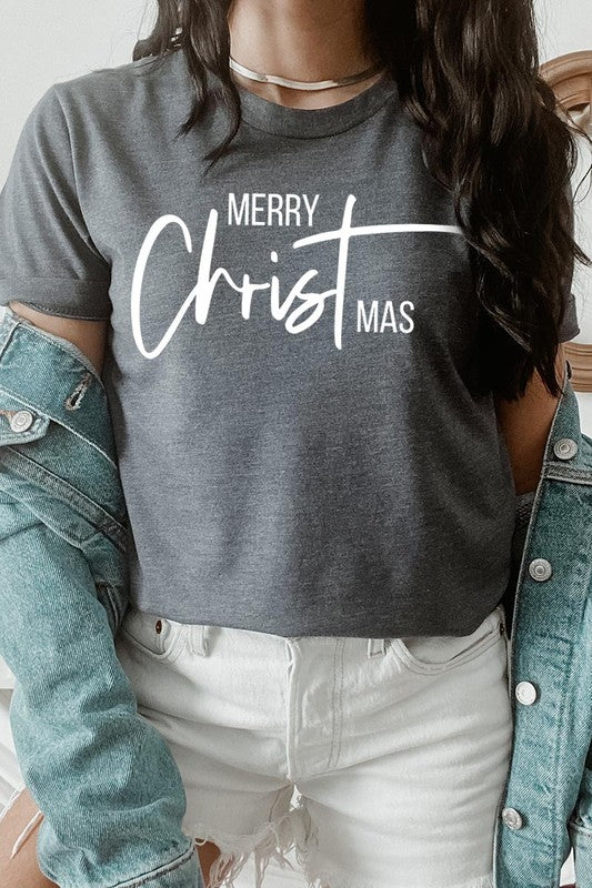 A woman with long blonde hair is smiling while wearing a Merry Christmas Graphic Tee featuring "Merry Christmas" in white script. This unisex crew neck tee boasts a high-quality direct-to-film printed graphic design that ensures vibrant and lasting colors.