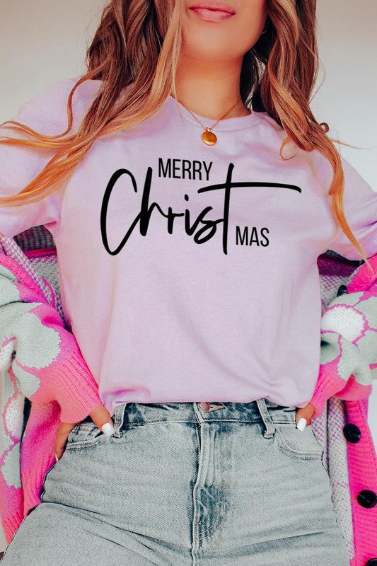 A woman with long blonde hair is smiling while wearing a Merry Christmas Graphic Tee featuring "Merry Christmas" in white script. This unisex crew neck tee boasts a high-quality direct-to-film printed graphic design that ensures vibrant and lasting colors.