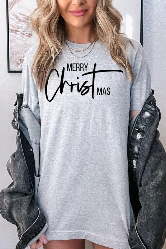 A woman with long blonde hair is smiling while wearing a Merry Christmas Graphic Tee featuring "Merry Christmas" in white script. This unisex crew neck tee boasts a high-quality direct-to-film printed graphic design that ensures vibrant and lasting colors.