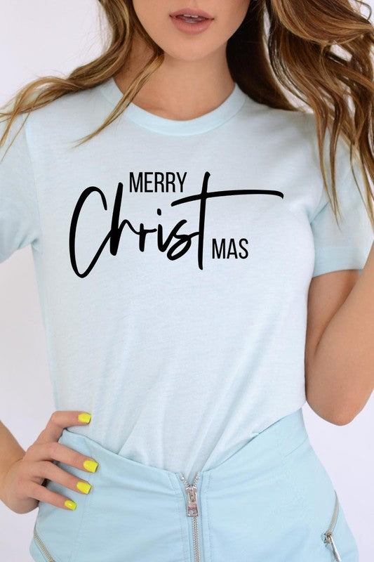 A woman with long blonde hair is smiling while wearing a Merry Christmas Graphic Tee featuring "Merry Christmas" in white script. This unisex crew neck tee boasts a high-quality direct-to-film printed graphic design that ensures vibrant and lasting colors.