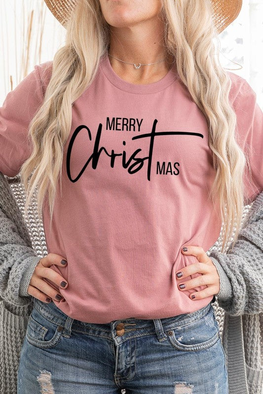 A woman with long blonde hair is smiling while wearing a Merry Christmas Graphic Tee featuring "Merry Christmas" in white script. This unisex crew neck tee boasts a high-quality direct-to-film printed graphic design that ensures vibrant and lasting colors.