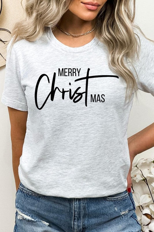 A woman with long blonde hair is smiling while wearing a Merry Christmas Graphic Tee featuring "Merry Christmas" in white script. This unisex crew neck tee boasts a high-quality direct-to-film printed graphic design that ensures vibrant and lasting colors.