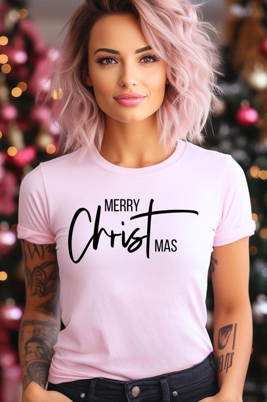 A woman with long blonde hair is smiling while wearing a Merry Christmas Graphic Tee featuring "Merry Christmas" in white script. This unisex crew neck tee boasts a high-quality direct-to-film printed graphic design that ensures vibrant and lasting colors.