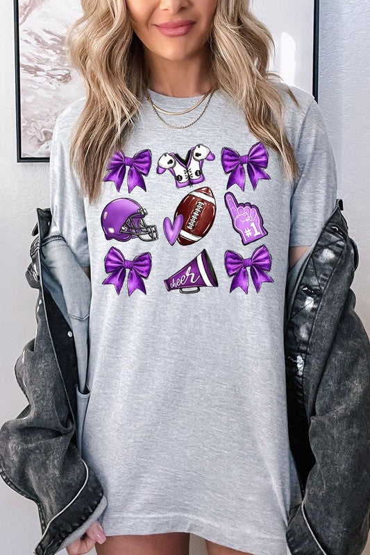 Someone wearing a Purple Coquette Football Graphic Tee, a unisex crew neck pink t-shirt decorated with sports-themed illustrations like a football, helmet, megaphone, foam finger, and cheerleading accessories in purple and white.