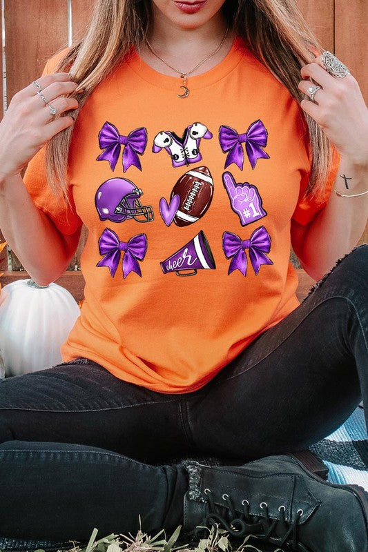 Someone wearing a Purple Coquette Football Graphic Tee, a unisex crew neck pink t-shirt decorated with sports-themed illustrations like a football, helmet, megaphone, foam finger, and cheerleading accessories in purple and white.