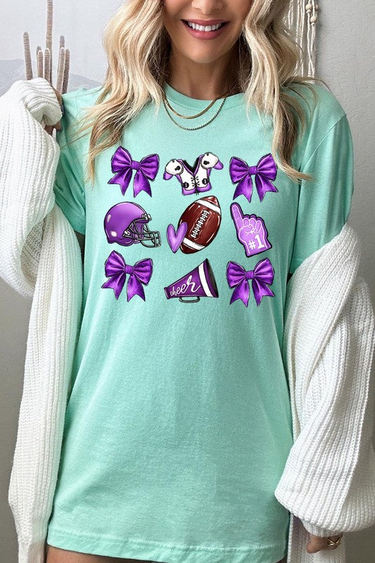 Someone wearing a Purple Coquette Football Graphic Tee, a unisex crew neck pink t-shirt decorated with sports-themed illustrations like a football, helmet, megaphone, foam finger, and cheerleading accessories in purple and white.