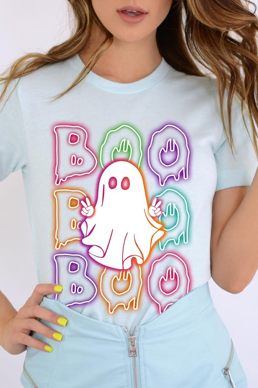 A person in a Boo Neon Halloween Ghost Graphic Tee, featuring neon letters spelling "BOO" with a cartoon ghost in the center. They are wearing light blue jeans and have a beige jacket draped over their arms.