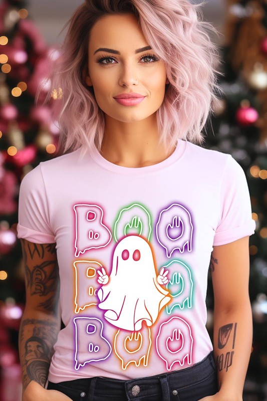 A person in a Boo Neon Halloween Ghost Graphic Tee, featuring neon letters spelling "BOO" with a cartoon ghost in the center. They are wearing light blue jeans and have a beige jacket draped over their arms.