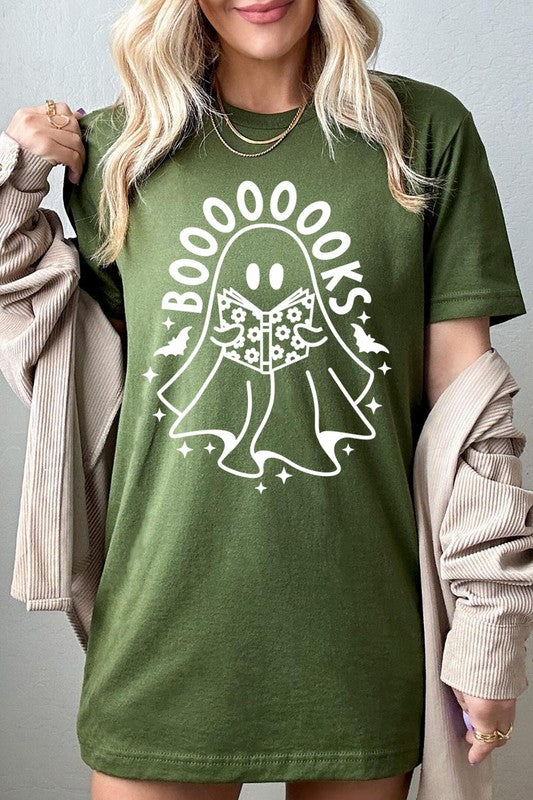 A person in a Cute Ghost Book Lover Graphic Tee featuring the text "BOOOOOOKS" holds a "Spells & Potions" book, set against a background of small bat decorations.