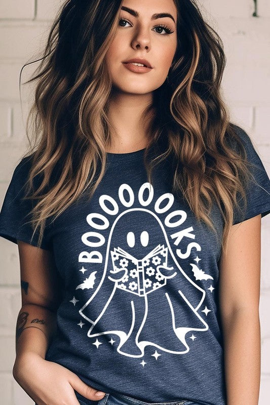 A person in a Cute Ghost Book Lover Graphic Tee featuring the text "BOOOOOOKS" holds a "Spells & Potions" book, set against a background of small bat decorations.