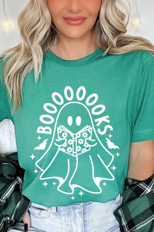 A person in a Cute Ghost Book Lover Graphic Tee featuring the text "BOOOOOOKS" holds a "Spells & Potions" book, set against a background of small bat decorations.