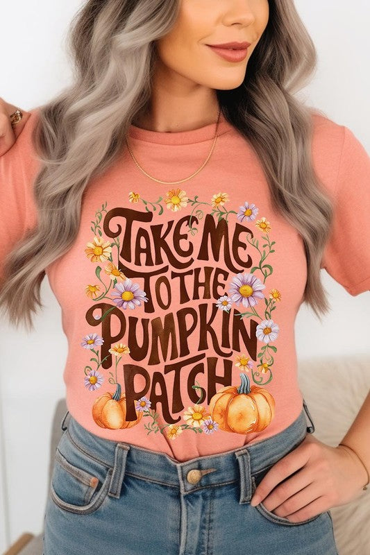 Person wearing a Take Me To The Pumpkin Patch Graphic Tee, which is a navy blue unisex crew neck t-shirt featuring the words "Take me to the pumpkin patch" surrounded by flowers and pumpkins.