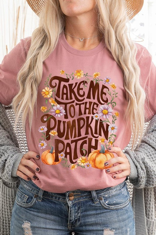 Person wearing a Take Me To The Pumpkin Patch Graphic Tee, which is a navy blue unisex crew neck t-shirt featuring the words "Take me to the pumpkin patch" surrounded by flowers and pumpkins.