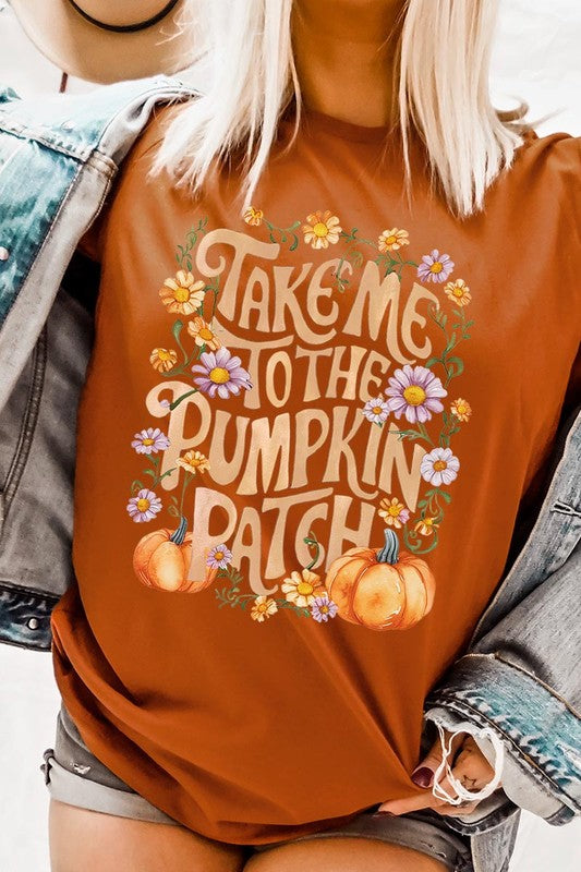 Person wearing a Take Me To The Pumpkin Patch Graphic Tee, which is a navy blue unisex crew neck t-shirt featuring the words "Take me to the pumpkin patch" surrounded by flowers and pumpkins.