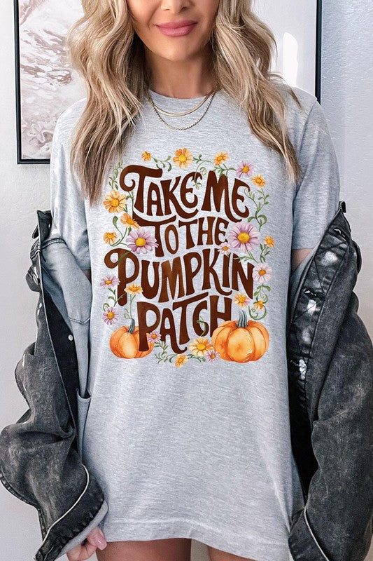 Person wearing a Take Me To The Pumpkin Patch Graphic Tee, which is a navy blue unisex crew neck t-shirt featuring the words "Take me to the pumpkin patch" surrounded by flowers and pumpkins.