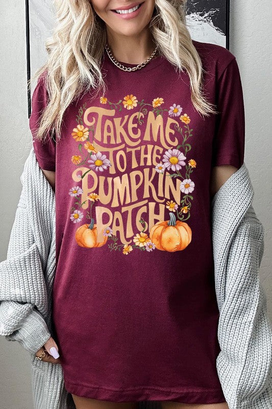 Person wearing a Take Me To The Pumpkin Patch Graphic Tee, which is a navy blue unisex crew neck t-shirt featuring the words "Take me to the pumpkin patch" surrounded by flowers and pumpkins.