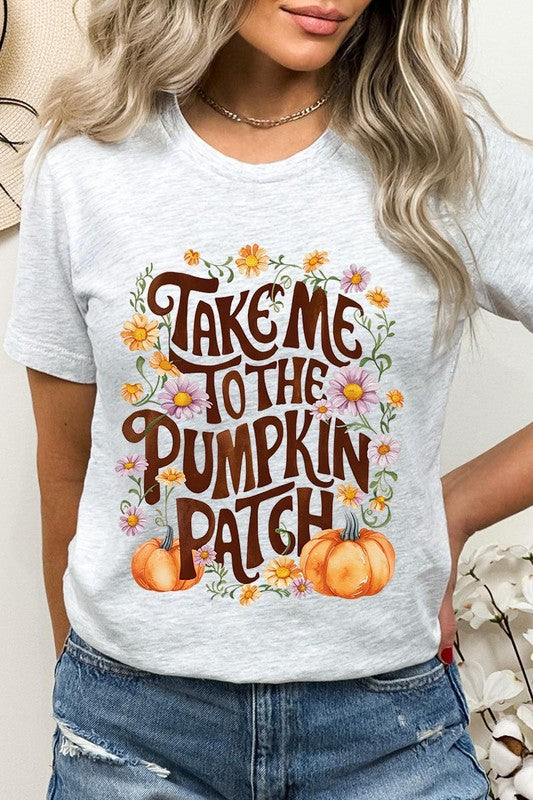 Person wearing a Take Me To The Pumpkin Patch Graphic Tee, which is a navy blue unisex crew neck t-shirt featuring the words "Take me to the pumpkin patch" surrounded by flowers and pumpkins.