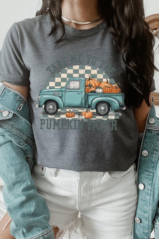 A woman wearing the "Take Me To The Pumpkin Patch Graphic Tee" featuring an illustration of a teal truck carrying pumpkins and the text "Take Me to the Pumpkin Patch." She has a green plaid shirt draped over her shoulders, creating a perfect match for Family Group Uniforms.