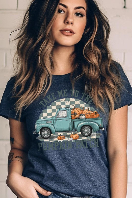 A woman wearing the "Take Me To The Pumpkin Patch Graphic Tee" featuring an illustration of a teal truck carrying pumpkins and the text "Take Me to the Pumpkin Patch." She has a green plaid shirt draped over her shoulders, creating a perfect match for Family Group Uniforms.