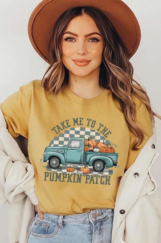 A woman wearing the "Take Me To The Pumpkin Patch Graphic Tee" featuring an illustration of a teal truck carrying pumpkins and the text "Take Me to the Pumpkin Patch." She has a green plaid shirt draped over her shoulders, creating a perfect match for Family Group Uniforms.