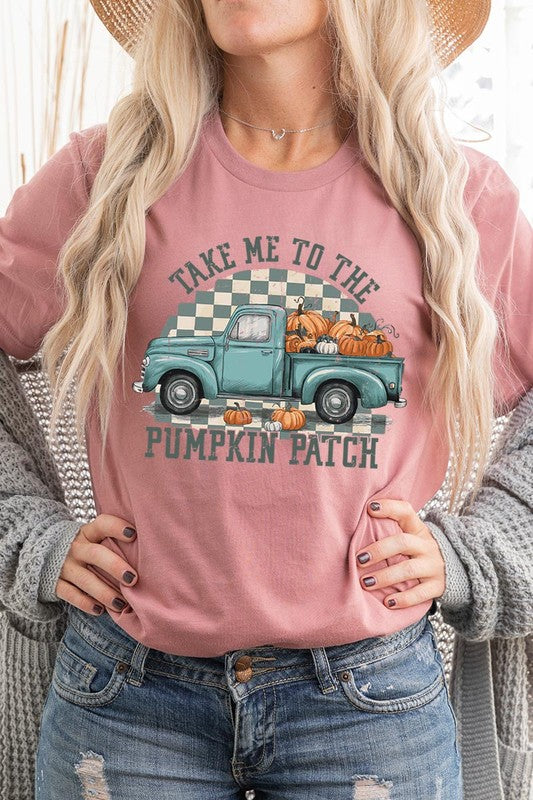 A woman wearing the "Take Me To The Pumpkin Patch Graphic Tee" featuring an illustration of a teal truck carrying pumpkins and the text "Take Me to the Pumpkin Patch." She has a green plaid shirt draped over her shoulders, creating a perfect match for Family Group Uniforms.