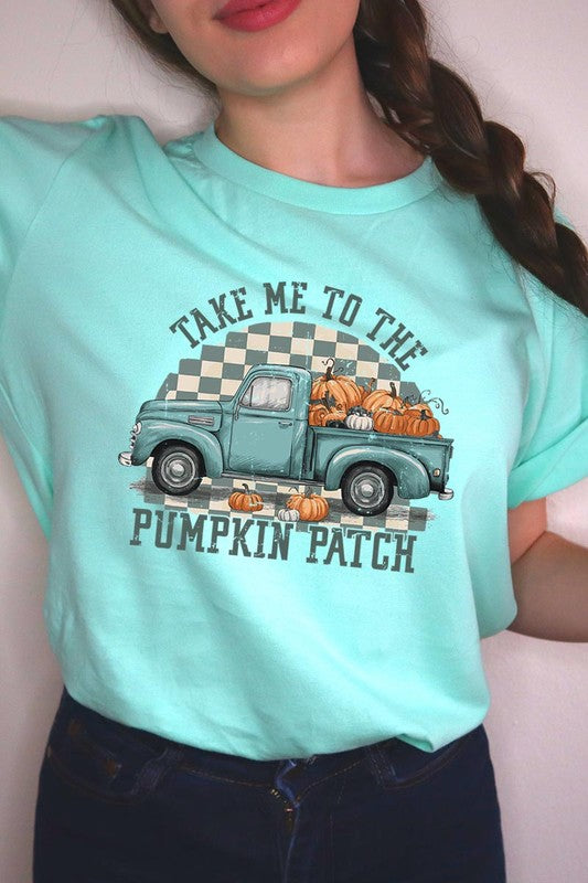 A woman wearing the "Take Me To The Pumpkin Patch Graphic Tee" featuring an illustration of a teal truck carrying pumpkins and the text "Take Me to the Pumpkin Patch." She has a green plaid shirt draped over her shoulders, creating a perfect match for Family Group Uniforms.