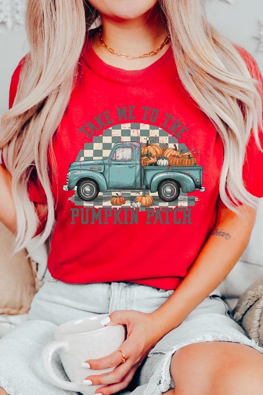 A woman wearing the "Take Me To The Pumpkin Patch Graphic Tee" featuring an illustration of a teal truck carrying pumpkins and the text "Take Me to the Pumpkin Patch." She has a green plaid shirt draped over her shoulders, creating a perfect match for Family Group Uniforms.