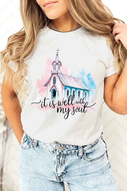 A woman wearing the "It Is Well With My Soul" graphic tee, featuring a grey color with an illustration of a church and the text "it is well with my soul.