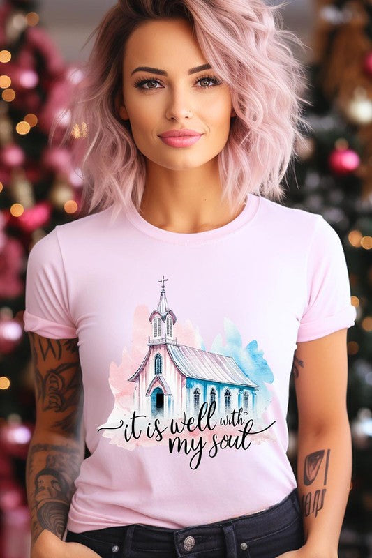 A woman wearing the "It Is Well With My Soul" graphic tee, featuring a grey color with an illustration of a church and the text "it is well with my soul.