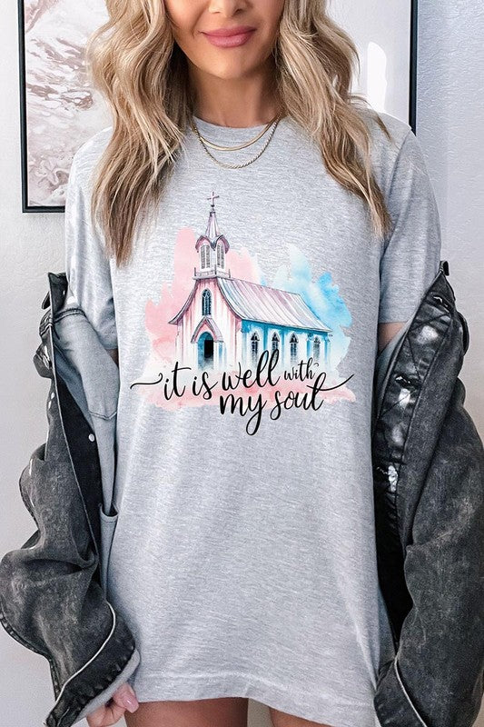 A woman wearing the "It Is Well With My Soul" graphic tee, featuring a grey color with an illustration of a church and the text "it is well with my soul.