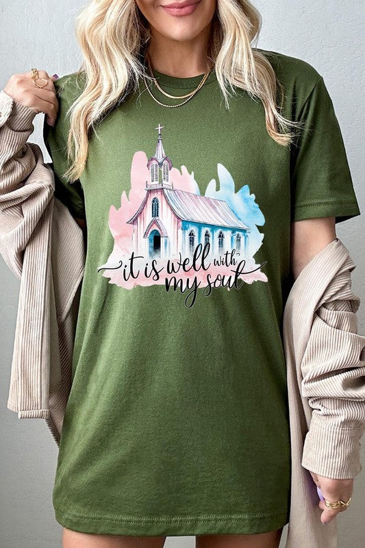 A woman wearing the "It Is Well With My Soul" graphic tee, featuring a grey color with an illustration of a church and the text "it is well with my soul.