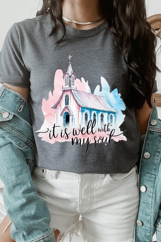 A woman wearing the "It Is Well With My Soul" graphic tee, featuring a grey color with an illustration of a church and the text "it is well with my soul.