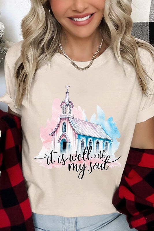 A woman wearing the "It Is Well With My Soul" graphic tee, featuring a grey color with an illustration of a church and the text "it is well with my soul.