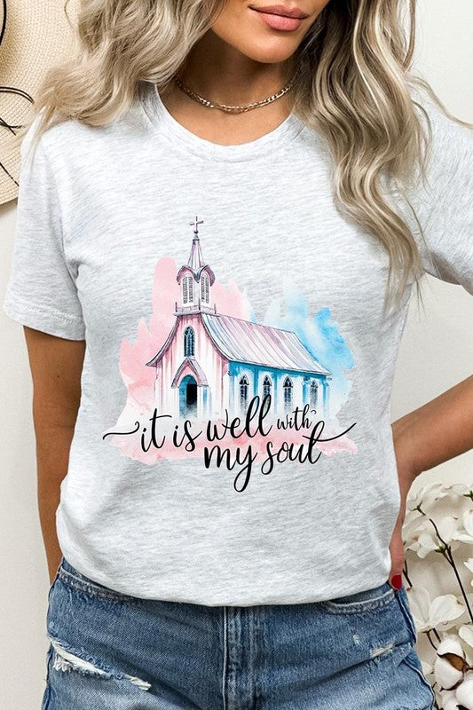 A woman wearing the "It Is Well With My Soul" graphic tee, featuring a grey color with an illustration of a church and the text "it is well with my soul.