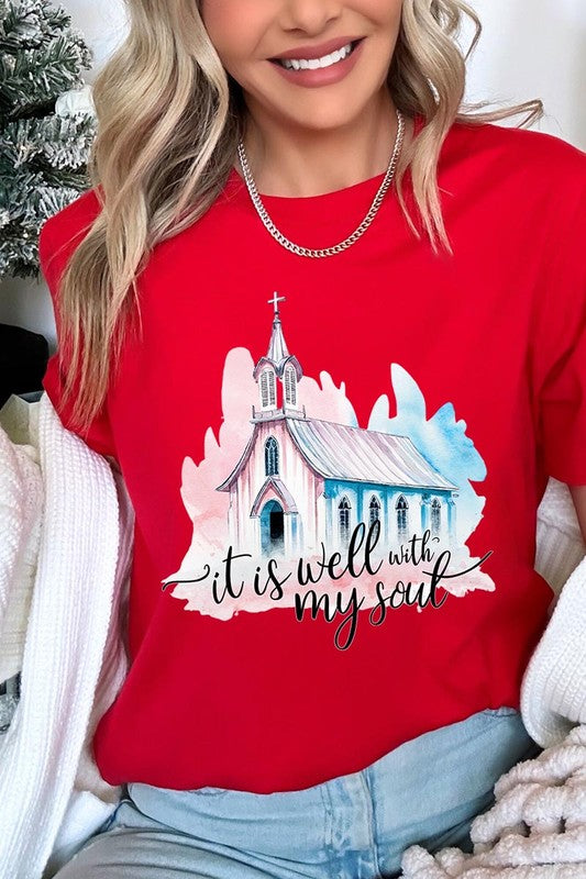 A woman wearing the "It Is Well With My Soul" graphic tee, featuring a grey color with an illustration of a church and the text "it is well with my soul.