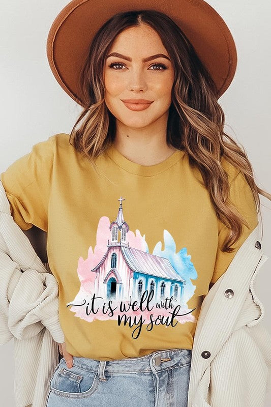 A woman wearing the "It Is Well With My Soul" graphic tee, featuring a grey color with an illustration of a church and the text "it is well with my soul.