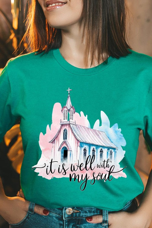 A woman wearing the "It Is Well With My Soul" graphic tee, featuring a grey color with an illustration of a church and the text "it is well with my soul.