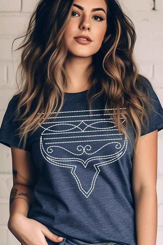 A person wearing the Western Boot Stitch Graphic Tee, featuring a geometric design and holding the bottom of the shirt, has a denim jacket draped over their shoulders.