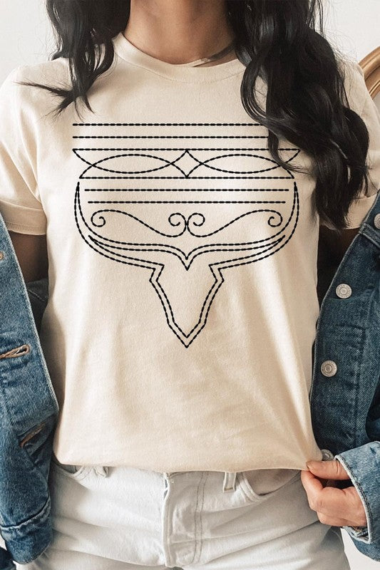 A person wearing the Western Boot Stitch Graphic Tee, featuring a geometric design and holding the bottom of the shirt, has a denim jacket draped over their shoulders.