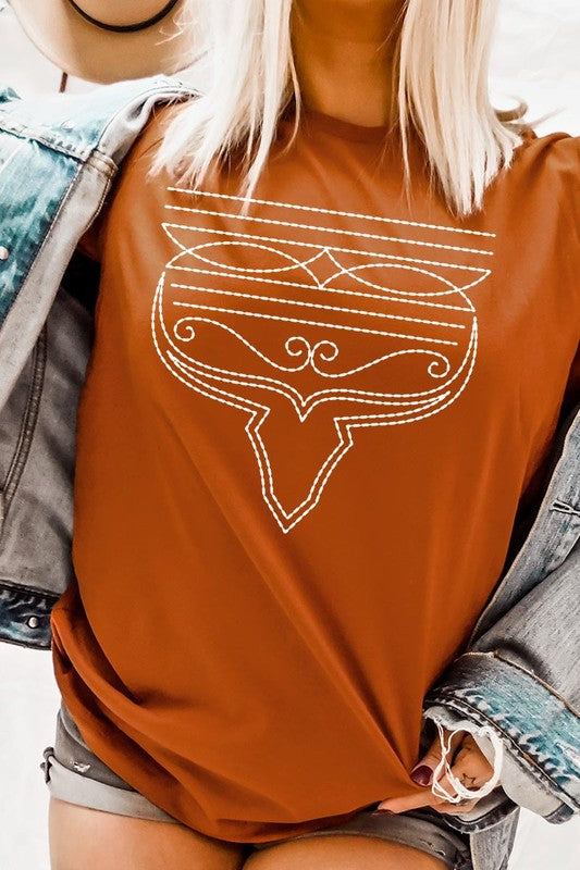 A person wearing the Western Boot Stitch Graphic Tee, featuring a geometric design and holding the bottom of the shirt, has a denim jacket draped over their shoulders.