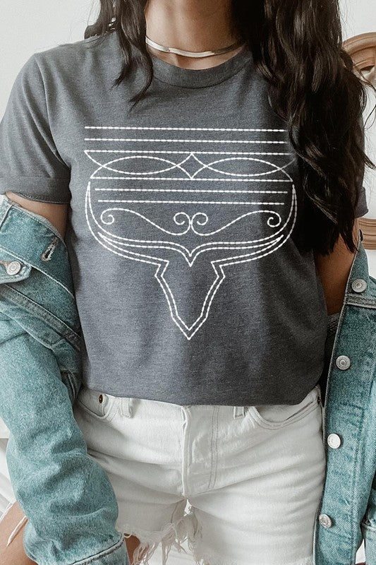 A person wearing the Western Boot Stitch Graphic Tee, featuring a geometric design and holding the bottom of the shirt, has a denim jacket draped over their shoulders.