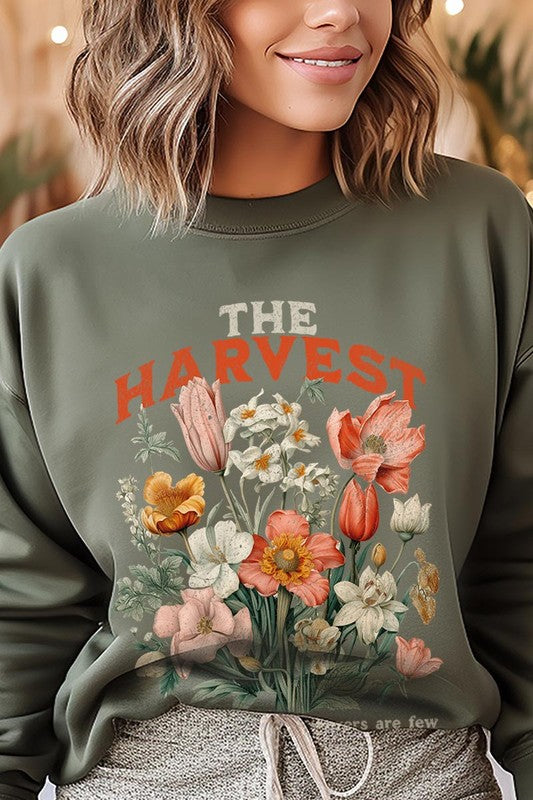 A person wearing 'The Harvest Christian Graphic Fleece Sweatshirt' in navy blue, adorned with floral graphics and the text "The Harvest" alongside "Matthew 9:37 - The harvest is plentiful, but the laborers are few," effortlessly combines style and comfort in this high-quality unisex crew neck.