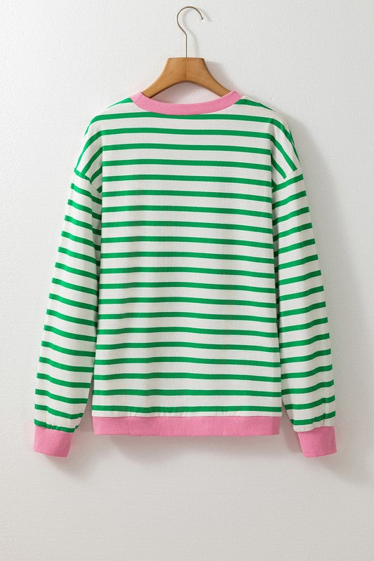 A person wearing the Cotton Stripe Drop Shoulder Sweatshirt, which features green stripes and pink cuffs, is facing away from the camera against a pink background.